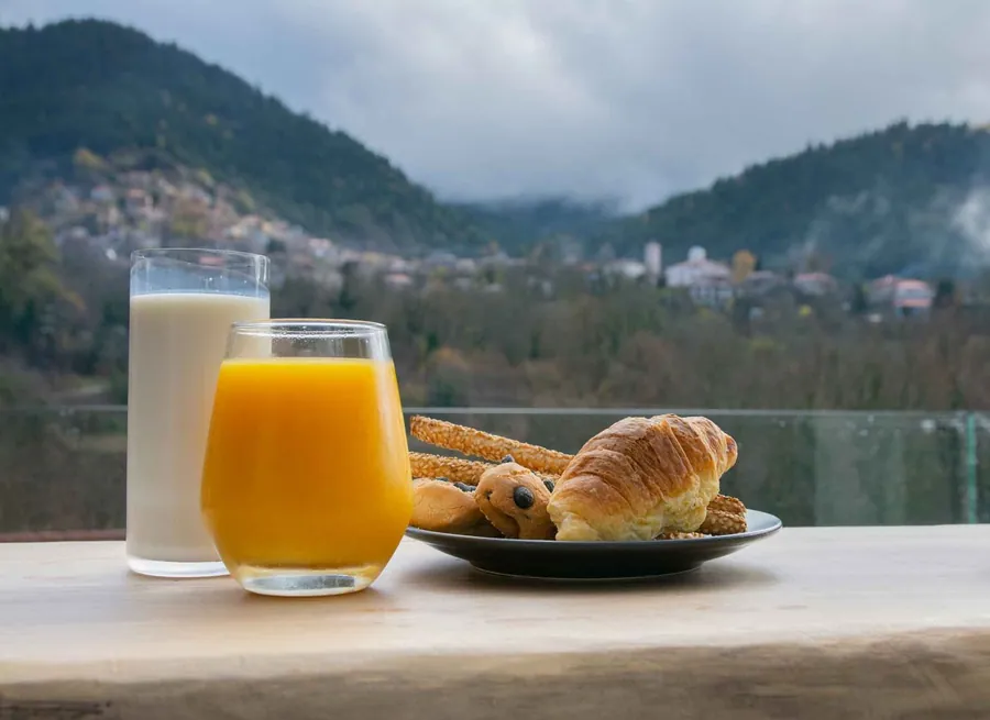 Χυμός πορτοκάλι, γάλα και κρουασάν με θέα στο βουνό